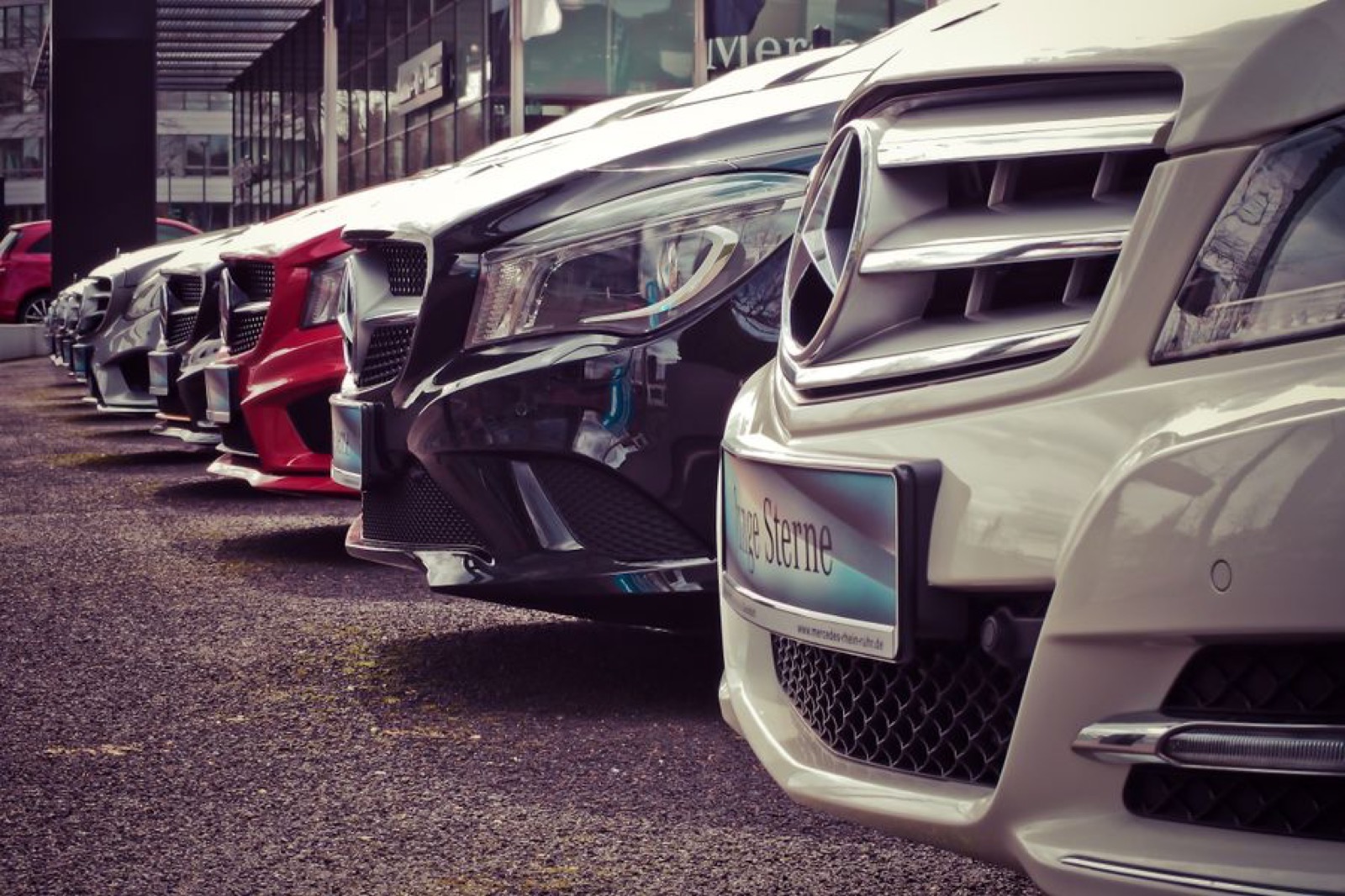 Vehicles waiting on a dealership lot at dusk
